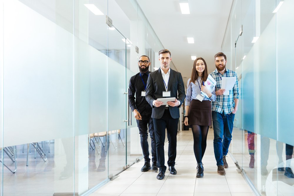 Full length of group of happy young business people walking the corridor in office together-1_RD